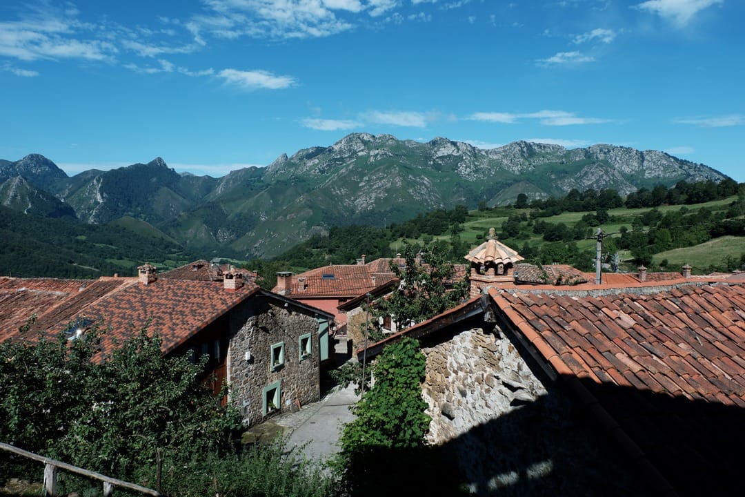 Ladines, with its tiled roofs and the Redes mountains in the background